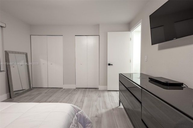 bedroom featuring multiple closets and light wood-type flooring