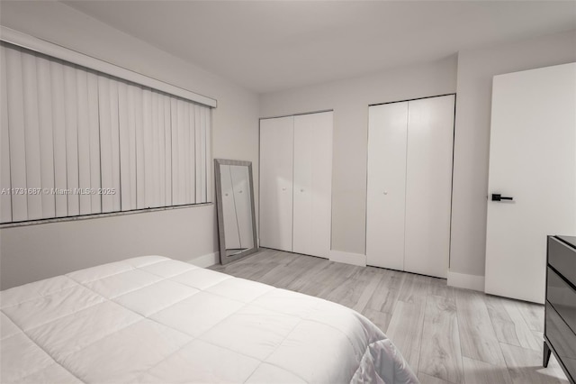 bedroom with two closets and light wood-type flooring