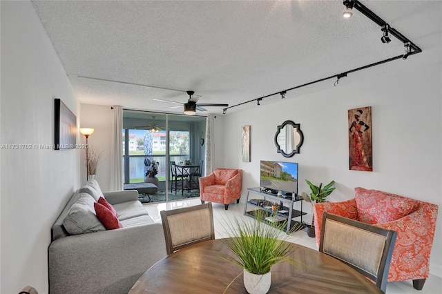 living room featuring ceiling fan, track lighting, and a textured ceiling