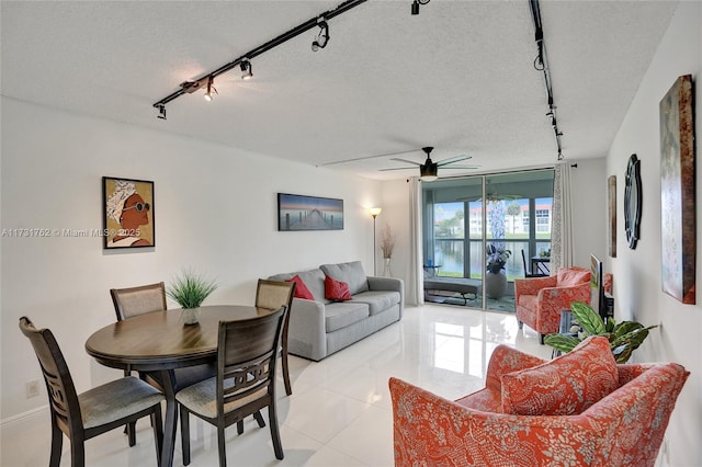 tiled dining space featuring expansive windows, rail lighting, ceiling fan, and a textured ceiling