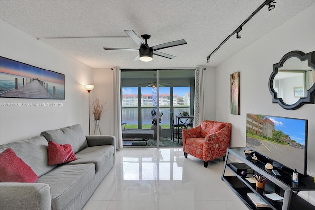 tiled living room with ceiling fan, rail lighting, floor to ceiling windows, and a textured ceiling