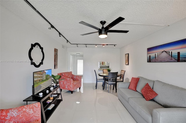 tiled living room featuring ceiling fan, rail lighting, and a textured ceiling