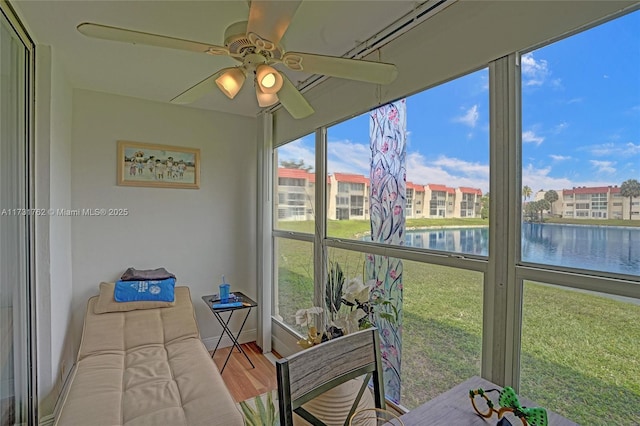 sunroom with plenty of natural light, ceiling fan, and a water view