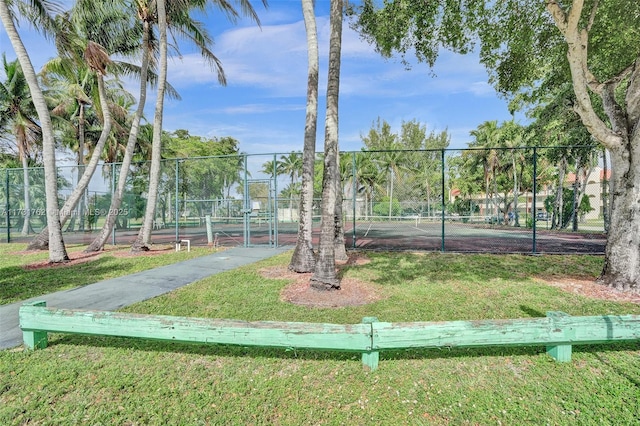 surrounding community featuring tennis court and a lawn