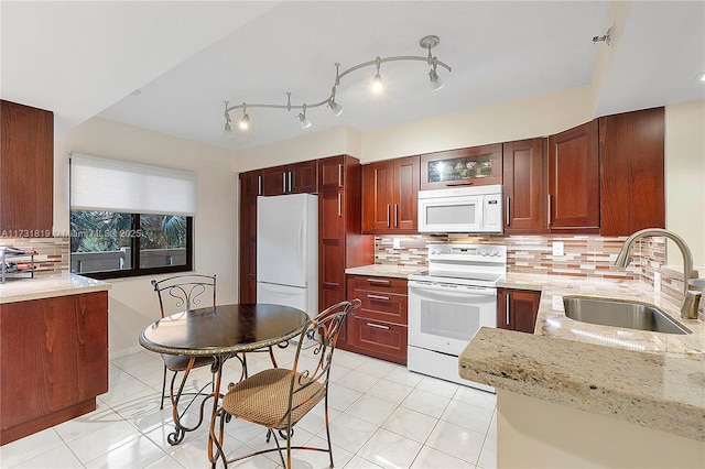 kitchen with sink, decorative backsplash, light tile patterned floors, light stone countertops, and white appliances