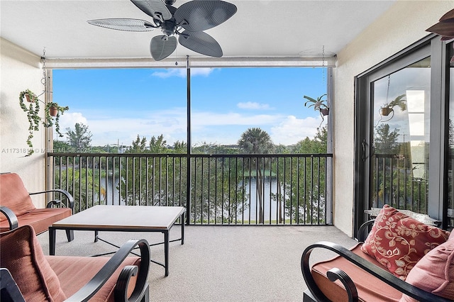 sunroom featuring a water view, ceiling fan, and a healthy amount of sunlight