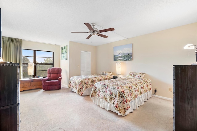 carpeted bedroom with ceiling fan, a closet, and a textured ceiling