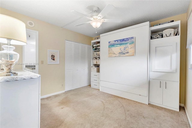 unfurnished bedroom featuring light colored carpet, a textured ceiling, ceiling fan, and a closet