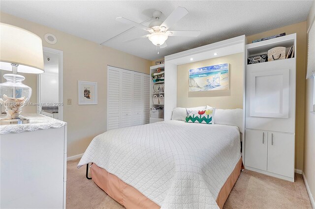 carpeted bedroom with a textured ceiling, a closet, and ceiling fan