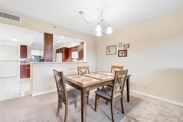 dining area featuring light colored carpet, a textured ceiling, and a notable chandelier