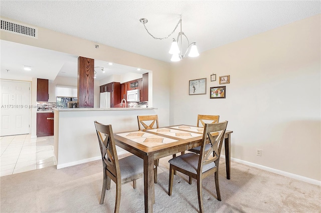 dining room featuring a textured ceiling, light carpet, and a notable chandelier