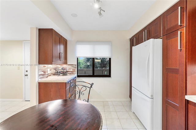 kitchen with white refrigerator, tasteful backsplash, light tile patterned floors, and track lighting