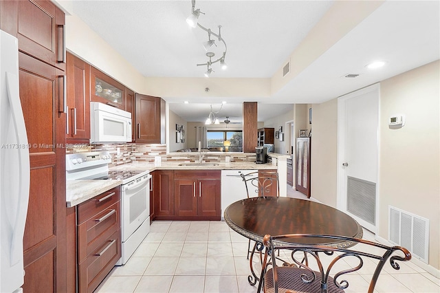 kitchen with light tile patterned flooring, tasteful backsplash, sink, kitchen peninsula, and white appliances