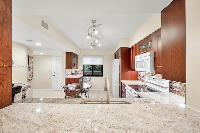 kitchen featuring sink, light stone counters, backsplash, and white appliances