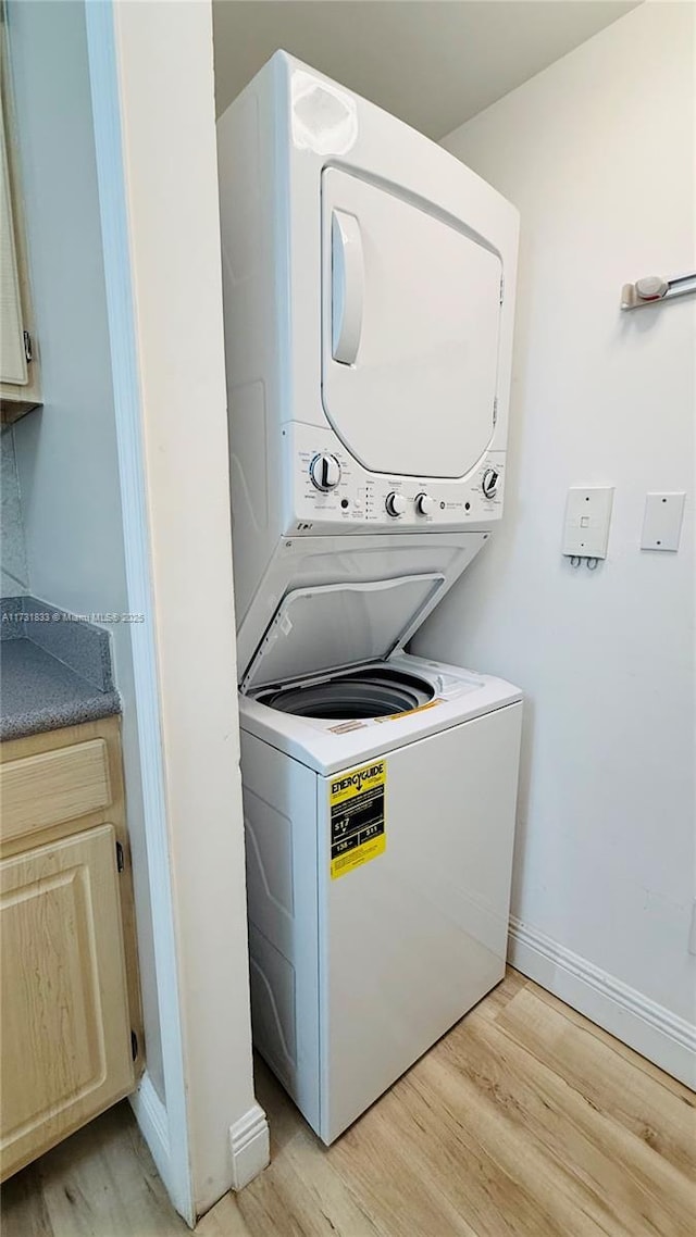 washroom featuring stacked washer and clothes dryer and light hardwood / wood-style floors