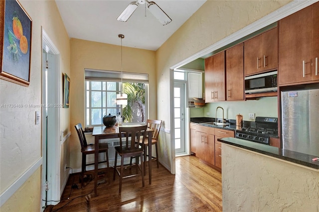 kitchen with pendant lighting, sink, dark hardwood / wood-style flooring, ceiling fan, and stainless steel appliances