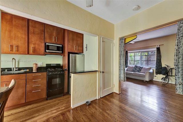 kitchen with appliances with stainless steel finishes, sink, and dark hardwood / wood-style flooring