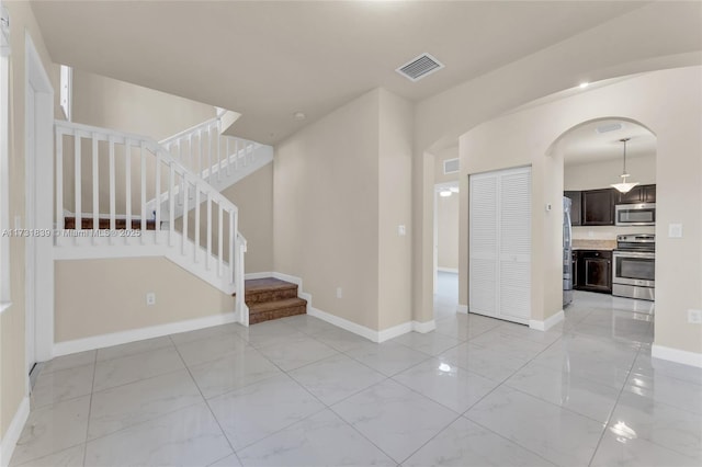 empty room with marble finish floor, baseboards, and visible vents