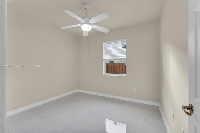 empty room featuring marble finish floor, ceiling fan, and baseboards