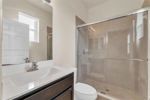 bathroom featuring toilet, a stall shower, and vanity