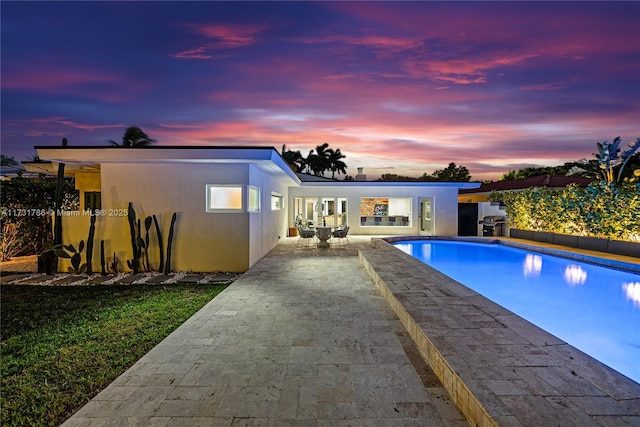 pool at dusk featuring a patio area