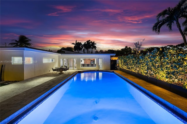 pool at dusk featuring a patio area