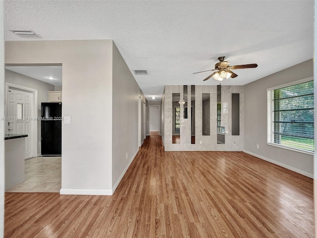 unfurnished room featuring a textured ceiling, light hardwood / wood-style floors, and ceiling fan