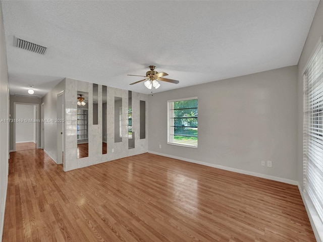 empty room featuring ceiling fan, light hardwood / wood-style flooring, and a textured ceiling