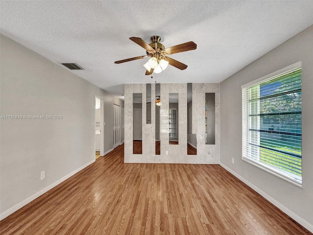 empty room featuring a textured ceiling, light hardwood / wood-style floors, and ceiling fan