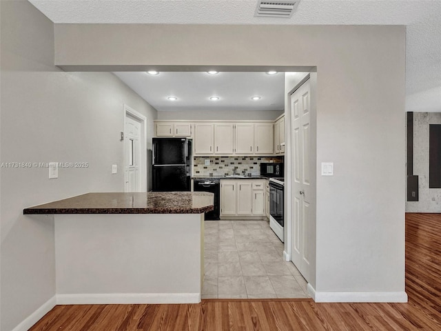 kitchen with tasteful backsplash, white cabinetry, black appliances, light hardwood / wood-style floors, and kitchen peninsula