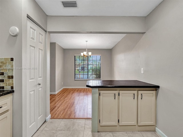 kitchen featuring light tile patterned flooring, decorative light fixtures, kitchen peninsula, a notable chandelier, and decorative backsplash