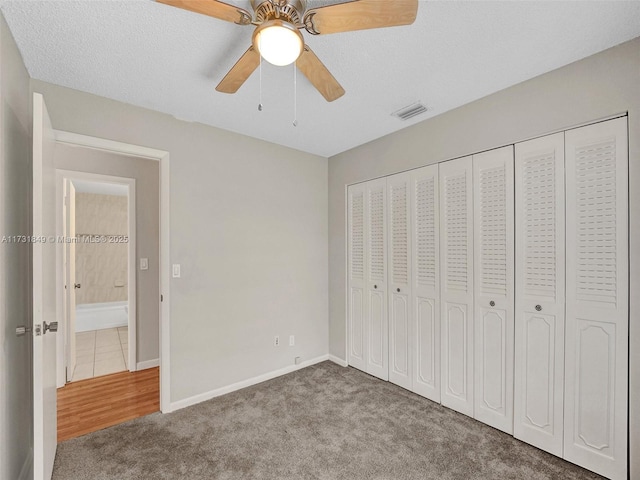 unfurnished bedroom with ceiling fan, light colored carpet, a closet, and a textured ceiling