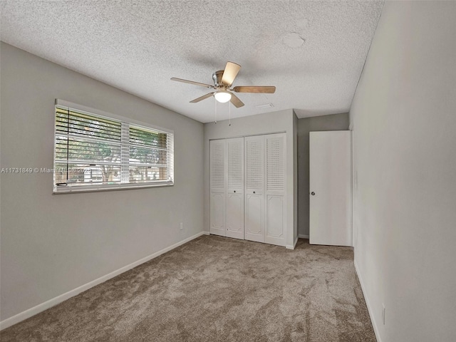 unfurnished bedroom featuring light colored carpet, a textured ceiling, ceiling fan, and a closet