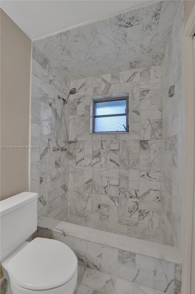 bathroom featuring a tile shower and toilet