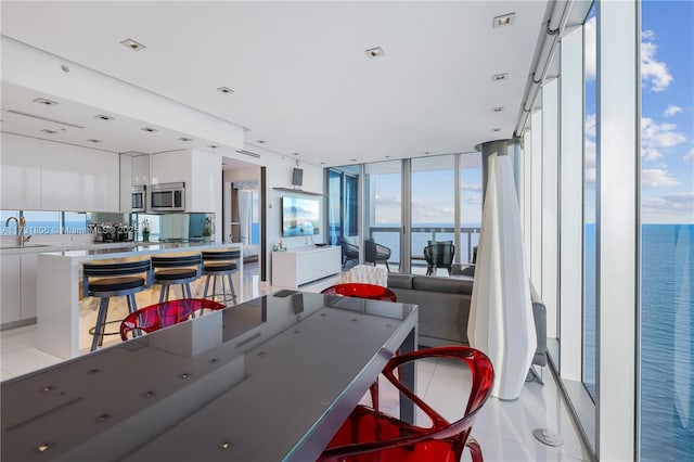 tiled dining space featuring sink, a wall of windows, plenty of natural light, and a water view