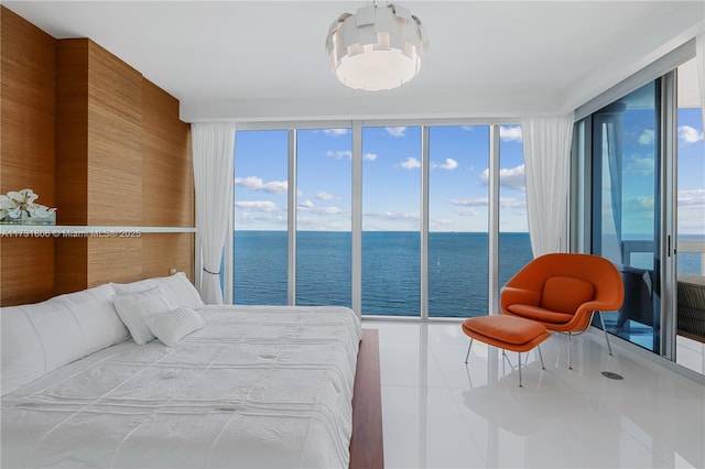 bedroom with a water view, tile patterned floors, a chandelier, and wood walls