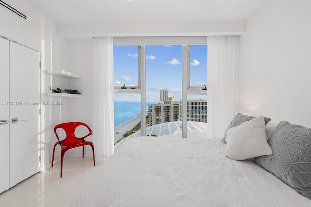 tiled bedroom with multiple windows, a water view, and access to exterior