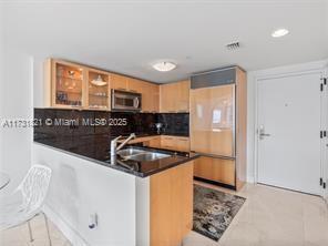 kitchen with light tile patterned flooring, sink, decorative backsplash, and kitchen peninsula