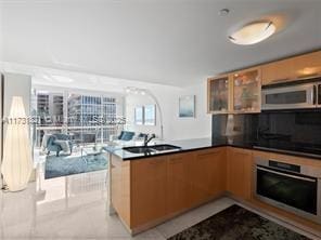 kitchen featuring light tile patterned flooring, stainless steel appliances, kitchen peninsula, and sink