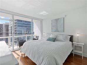 bedroom with dark hardwood / wood-style floors, access to outside, and floor to ceiling windows