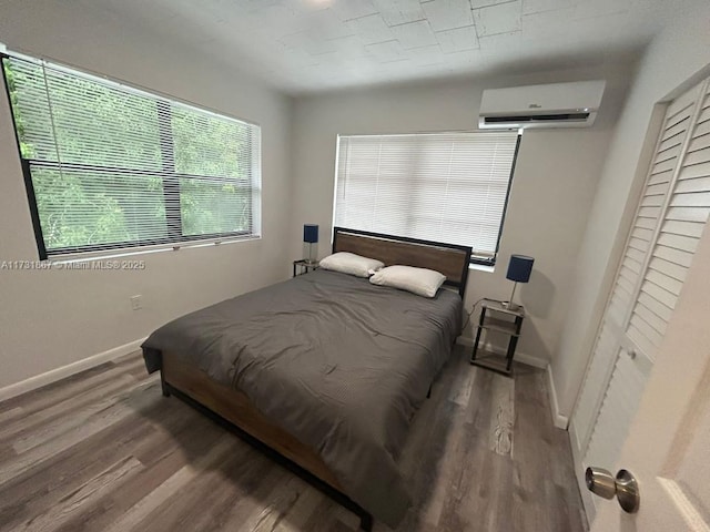 bedroom featuring wood-type flooring and an AC wall unit