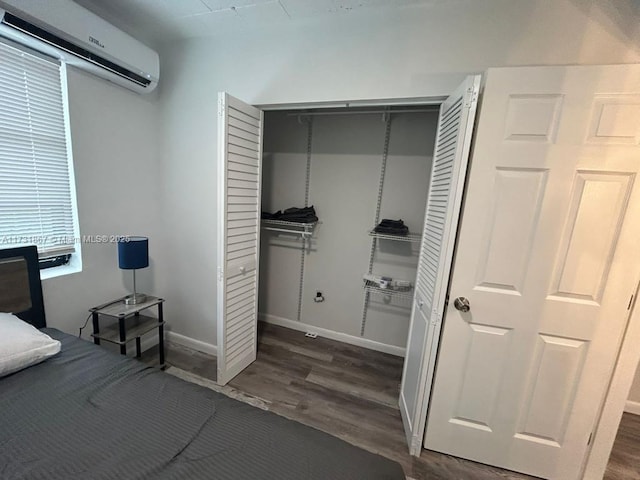 bedroom with dark wood-type flooring, a wall mounted air conditioner, and a closet