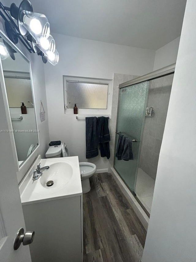 bathroom featuring vanity, toilet, a shower with shower door, and hardwood / wood-style floors