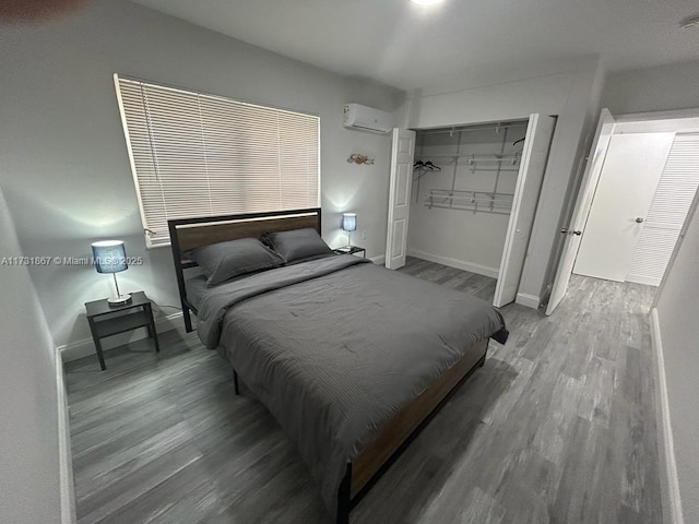 bedroom featuring hardwood / wood-style floors, a closet, and an AC wall unit