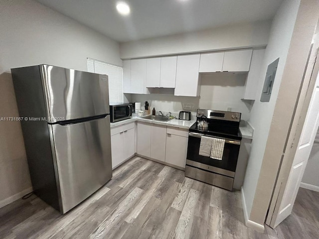 kitchen with stainless steel appliances, white cabinetry, sink, and light hardwood / wood-style floors