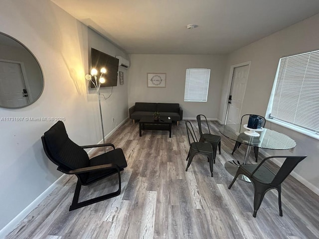 sitting room featuring wood-type flooring and a wall mounted air conditioner