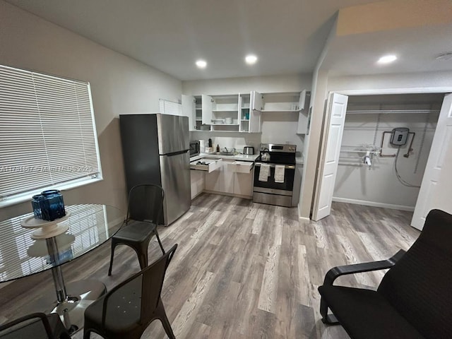 kitchen with white cabinetry, appliances with stainless steel finishes, sink, and light hardwood / wood-style floors