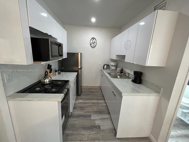 kitchen with stainless steel appliances, sink, white cabinets, and light wood-type flooring