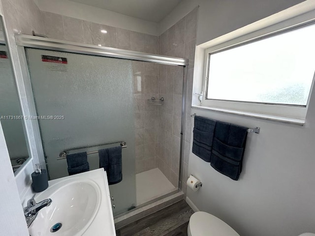 bathroom featuring toilet, wood-type flooring, a shower with door, and sink