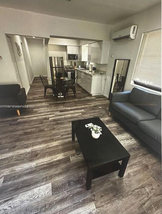 living room with dark hardwood / wood-style flooring and a wall unit AC